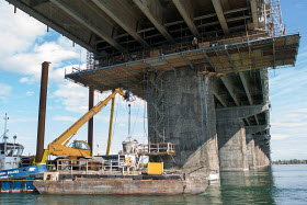 Près de 10 mois par année, les ouvriers sont à l'œuvre sous le pont Champlain. Ici, une barge de travail est arrimée à un pilier du pont en prévision de sa réparation. Crédit Groupe CNW et PJCCI